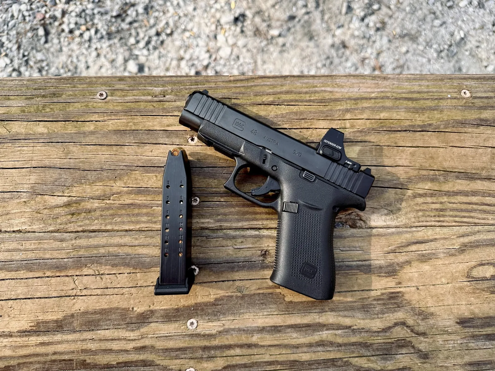 Pistola Glock con cargador sobre mesa de madera, fotografía editorial